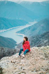 Naklejka na ściany i meble Beautiful Young Girl in a cosy red sweater on Mountain top