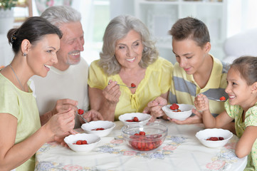 Portrait of big happy family eating fresh strawberries at kitchen
