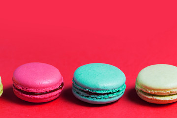Close up of baked three multicolored macaroons on pink background