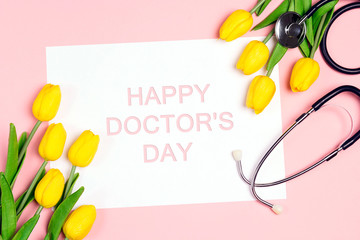 Doctor's day greeting card with yellow tulips and stethoscope on pink background.