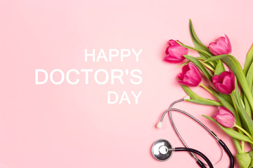 Doctor's day greeting card with bunch of tulips and stethoscope on pink background.