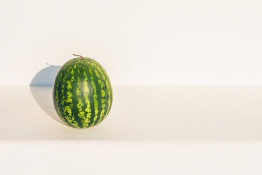 Watermelon on the stone bench on the white wall background.  Summer concept