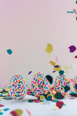 Funny multicolored easter eggs hand painted and splash of colorful papers in movement.