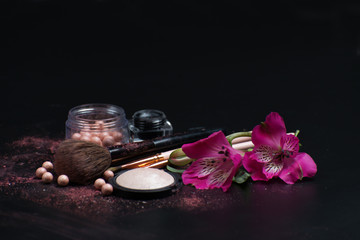 Cosmetics and flowers on a black background. Top view. Concept of beauty and personal care.