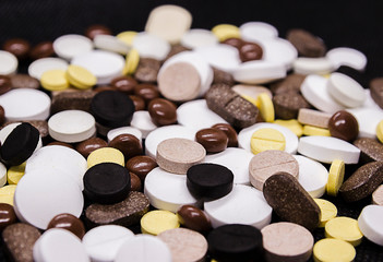 Many different pills unpacked on a black background
