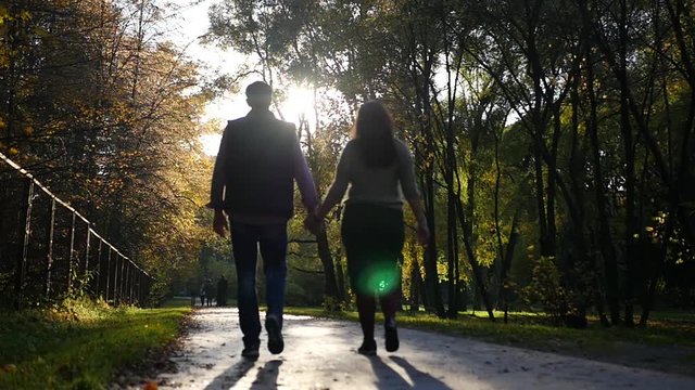 A loving couple walks in autumn park at sunset. HD, 1920x1080, slow motion