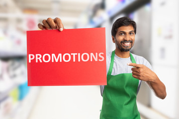 Supermarket employee holding promotions text on paper.