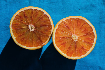 Blood orange cut in half on blue fabric background, top view.