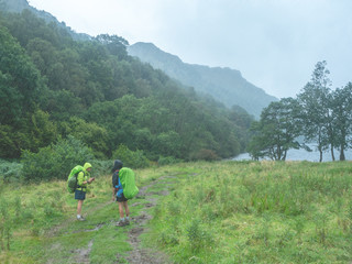 Obraz premium two girls with backpacks standing in the rain in the middle of nature