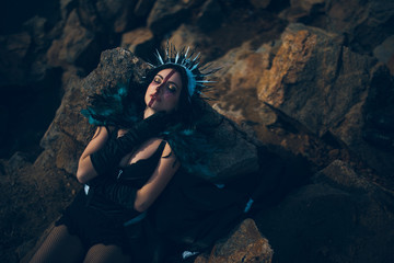A young woman in the image of a fairy and a sorceress lying on rock.
