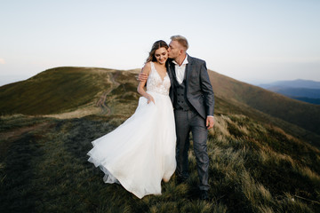 Beautiful wedding couple, bride and groom, in love on the background of mountains