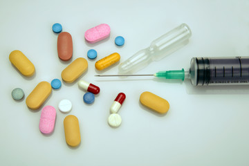 Medicine pills, capsules and syringe on white background