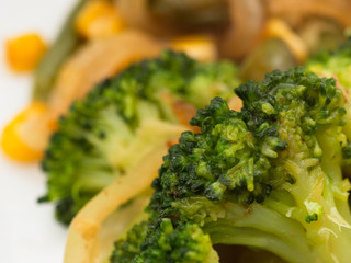 cooked vegetables broccoli, carrots, green beans, corn on a white plate. macro