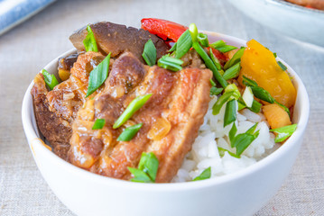 Bowl of rice with spicy pork and vegetables close up - traditional asian dish