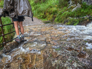 girl with backpack climbing on a railing to avoid getting wet feet