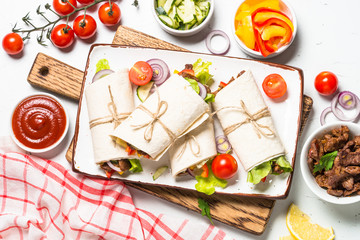 Burritos tortilla wraps with beef and vegetables on white.