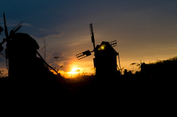 Silhouettes of old windmills on the background of bright blue sky sunset