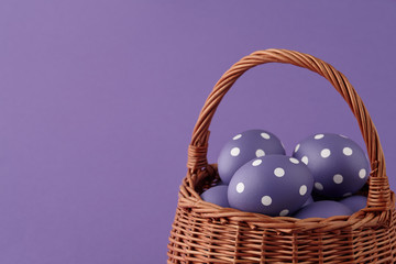 Wicker basket with purple painted Easter eggs with dots