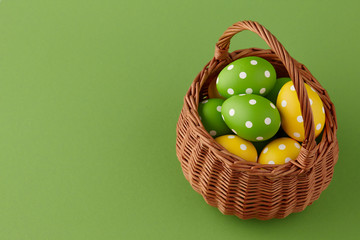 Wicker basket with yellow and green painted Easter eggs with dots