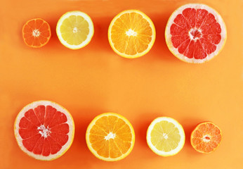 halved citrus fruits in a row on orange colored background