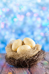 Three Easter eggs in the nest on wooden table and abstract bokeh background