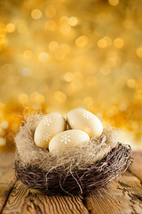 Easter eggs in the nest on wooden table and golden abstract background