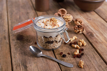 light healthy breakfast  with yogurt on oatmeal muesli and walnuts in a glas on a rustic wooden table. close up