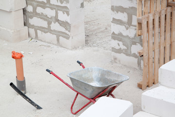 Construction site on which the walls are built of gas concrete blocks and wheelbarrow