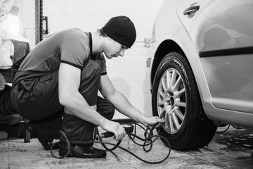 Fototapeta na wymiar car repair at a service station. A young man checks the tire pressure