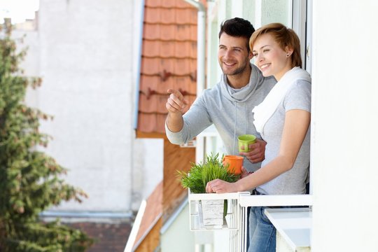 Happy couple searching distance from balcony