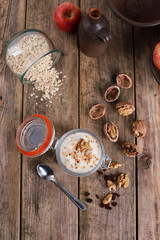 light healthy breakfast  with yogurt on oatmeal muesli and walnuts in a glas on a rustic wooden table. close up