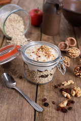 light healthy breakfast  with yogurt on oatmeal muesli , blueberries and walnuts in a glas on a rustic wooden table. close up