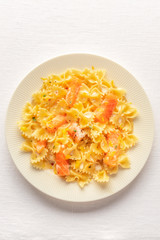 Smoked salmon with bowtie pasta. Farfalle with salmon and a cream sauce, shot from above on a white linen tablecloth with copy space