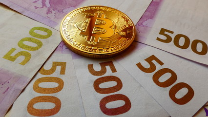 Bitcoins, an virtual currency in physical coin form, displayed on 500 Euro banknotes