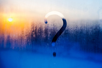 question mark on a misted window during sunset - background