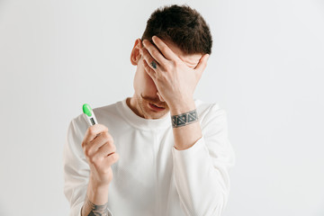 Upset man looking in pregnancy test. Human emotions concept