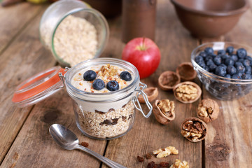 light healthy breakfast  with yogurt on oatmeal muesli , blueberries and walnuts in a glas on a rustic wooden table