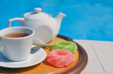 Chamomile tea in a cup in front of the pool.