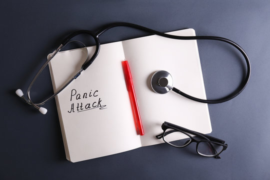 Panic attack and mental health awareness concept image with open notebook, glasses and pen, a lot of copy space for text on dark background. Close up, top view, flat lay.