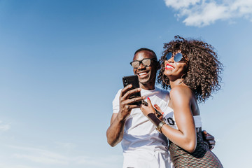 Two happy friends using the mobile in the street. Friendship concept.
