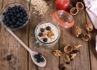 Healthy breakfast with yogurt on oatmeal muesli and walnuts, in a glas on a rustic wooden table.