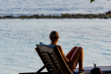 Junge Frau relaxt auf einem Liegestuhl am Meer
