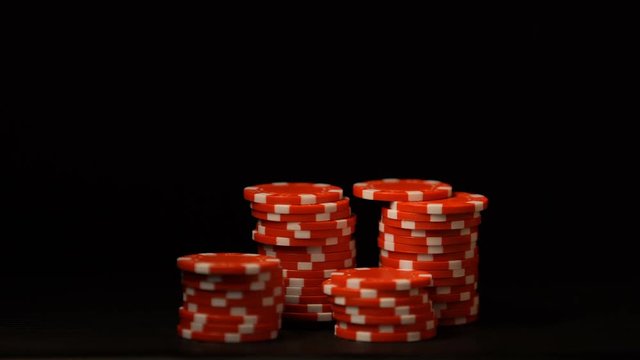 Hand putting red chips isolated on black, gambling addiction, casino business
