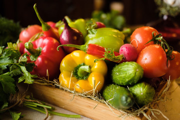 Group of fresh vegetables and herbs in wooden box on wooden background. Cucumber, paprika, pepper, cucumber, tomato and herbs. Harvest and healthy organic food concept