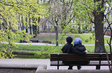 Fototapeta premium A couple of teenagers is sitting in a park in Riga, Latvia. The girl has trendy blue hair. 