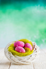 Easter eggs in the nest and wooden table on abstract background