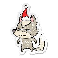 distressed sticker cartoon of a annoyed wolf wearing santa hat