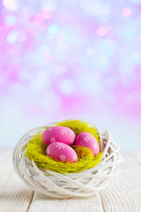 Easter eggs in the nest and wooden table on abstract background