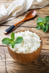 Homemade cottage cheese with mint in a bowl on old wooden table.