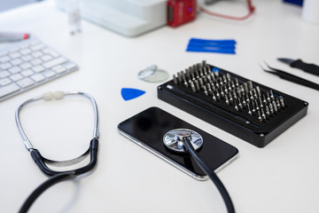 stethoscope, mobile phone and tool box on white desk in professional repair center